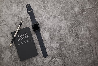 Minimalist flat lay of smartwatch, notebook, and pen on concrete