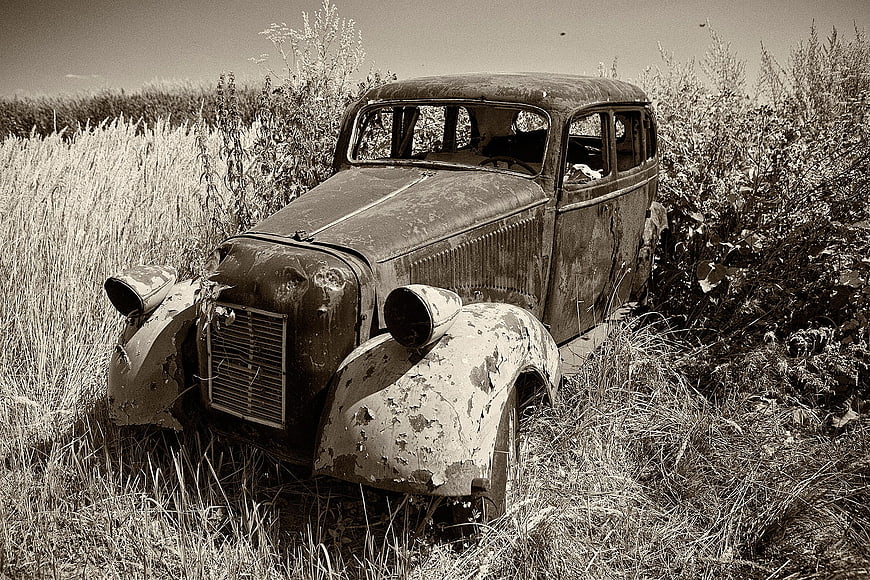 Abandoned vintage car in overgrown field