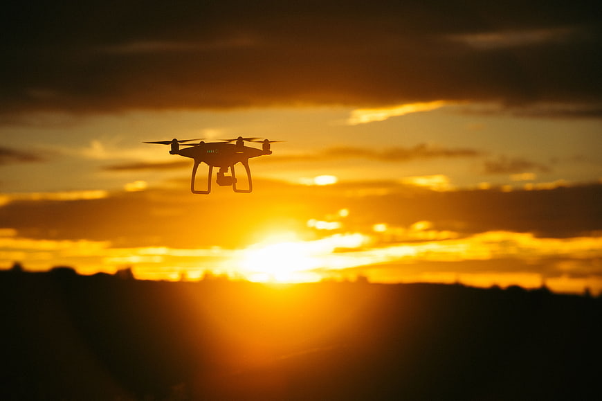 Silhouette of Drone Flying Against Golden Sunset Sky