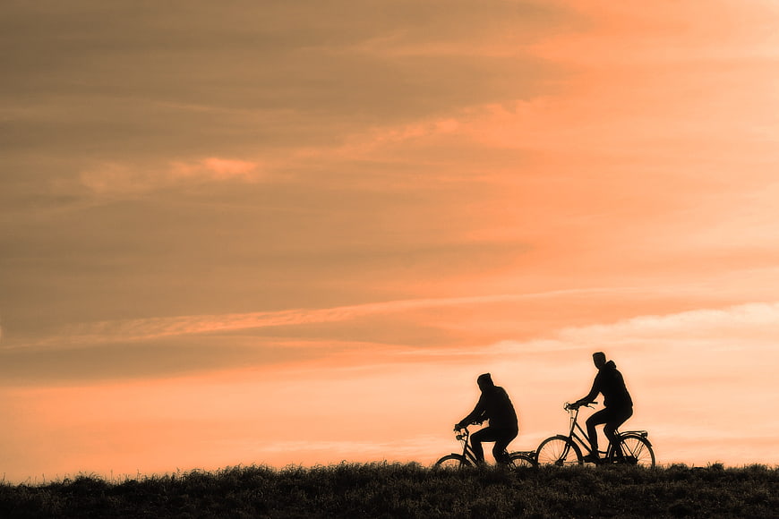 Silhouette of Two Cyclists Riding at Sunset