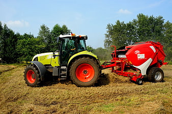 Claas Tractor Pulling Red Round Baler in Hayfield