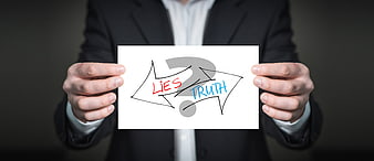 Businessman holding sign with arrows pointing to lies and truth