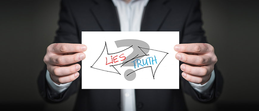 Businessman holding sign with arrows pointing to lies and truth