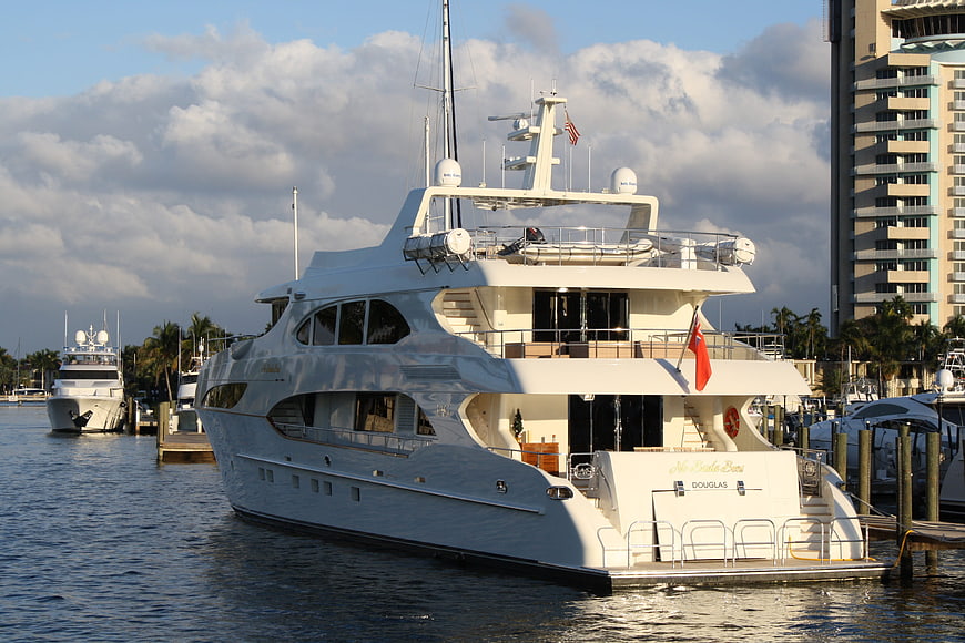 Luxury white yacht docked at marina with city skyline