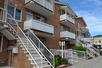 Row of brick apartment buildings with white balconies and stairs