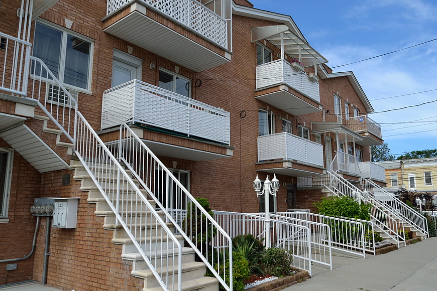 Row of brick apartment buildings with white balconies and stairs