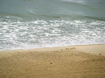 Aerial view of ocean waves crashing on sandy beach