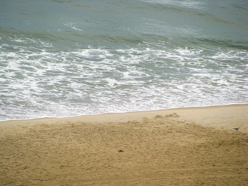 Aerial view of ocean waves crashing on sandy beach