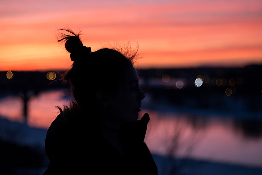 Silhouette of Woman Watching Sunset Over River