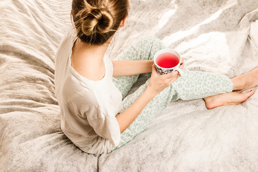Woman relaxing in bed with red tea