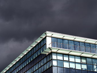 Modern Glass Building Corner Against Dark Stormy Sky