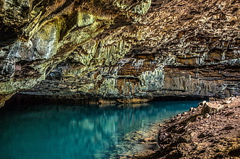 Turquoise water in a rocky sea cave with layered cliffs