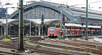 Red commuter train at Cologne Central Station with complex railway tracks