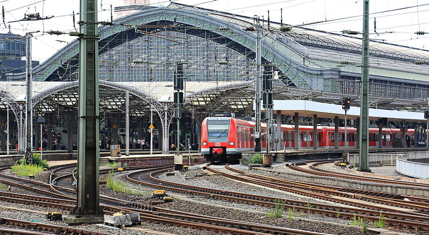 Red commuter train at Cologne Central Station with complex railway tracks