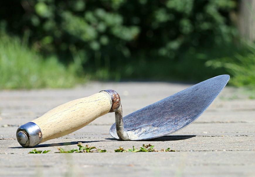 Old rusty trowel with wooden handle on concrete