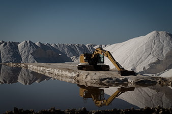Yellow Excavator Mining Salt Ponds with Reflection