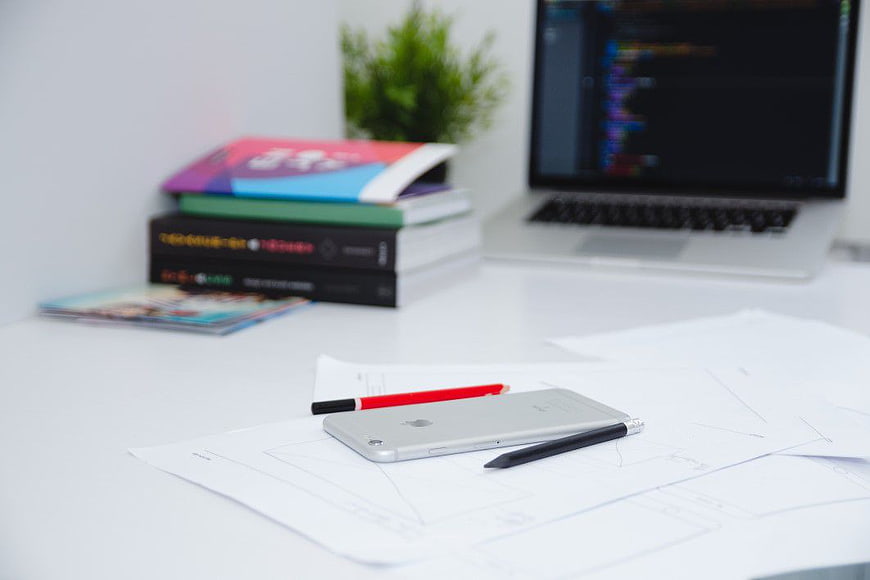 Minimalist Workspace with iPhone, Sketches, and Laptop