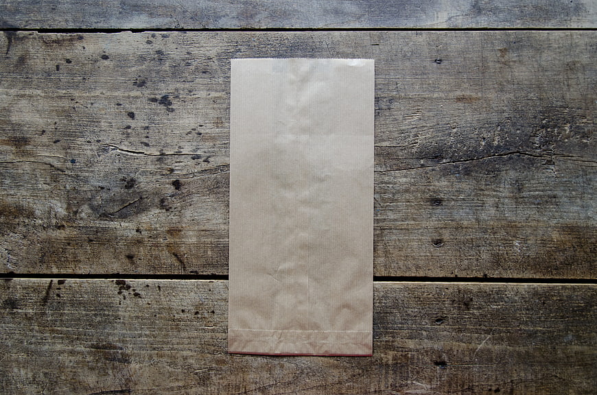 Empty brown paper bag on rustic wooden table background