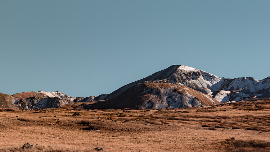 Snow-capped mountain peak with brown tundra foreground