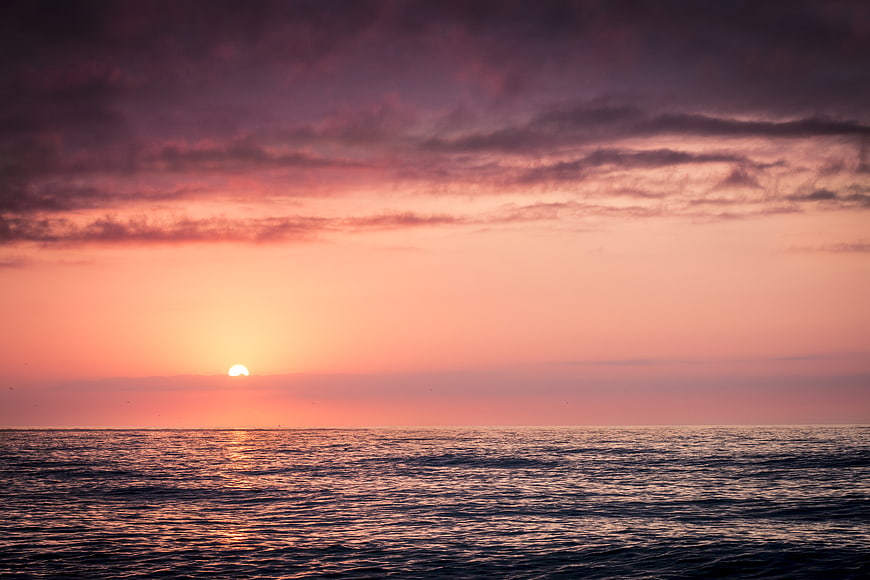 Serene Sunset Over Ocean with Pink and Purple Clouds