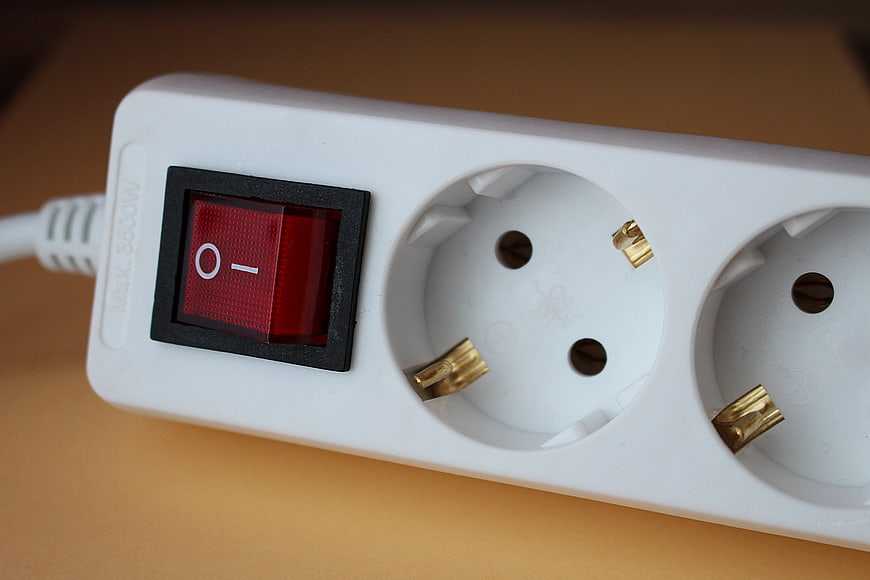 Close-up of white power strip with red switch and European sockets