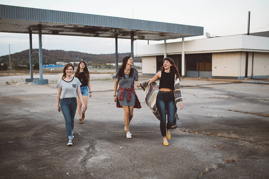 Four happy women walking and laughing in abandoned gas station
