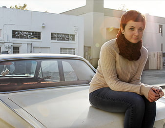 Woman Sitting on Vintage Car Hood in Urban Setting
