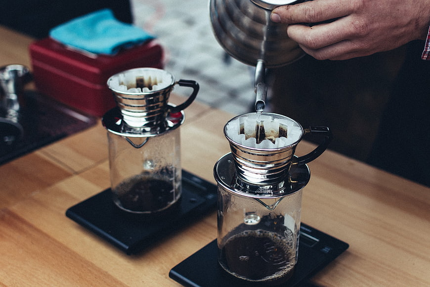 Barista pouring hot water into V60 coffee drippers