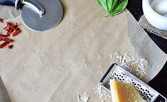 Pizza ingredients on parchment paper with grater and cutter