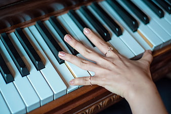 Woman's hand playing piano keys with diamond ring