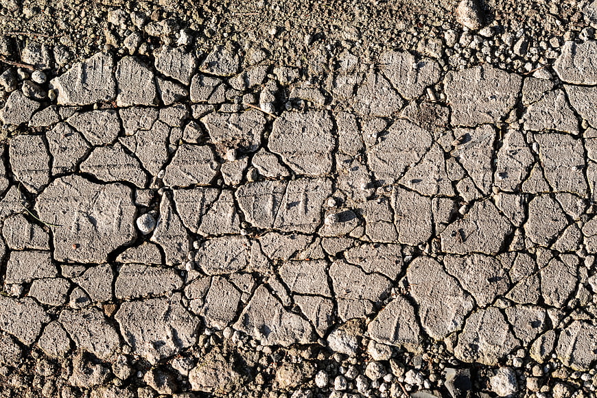 Close-up texture of cracked dry earth and gravel road surface