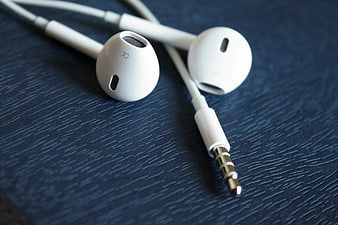 White Wired Earphones on Dark Blue Textured Surface