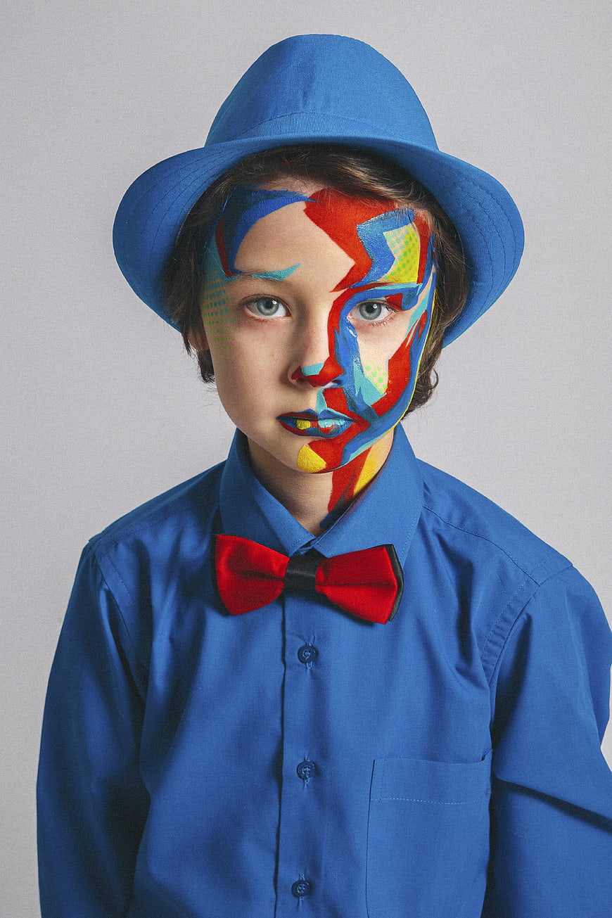 Creative Portrait of Boy with Abstract Face Paint and Blue Hat