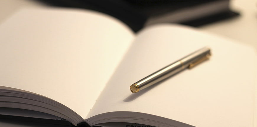 Silver pen on open blank notebook pages