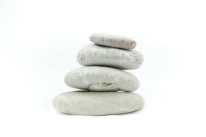 Stacked smooth gray stones on white background for zen meditation