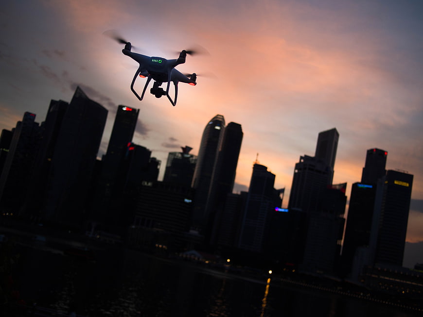 Drone Flying Over City Skyline at Sunset
