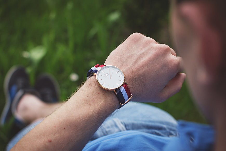 Man Checking Time on Wristwatch in Grass