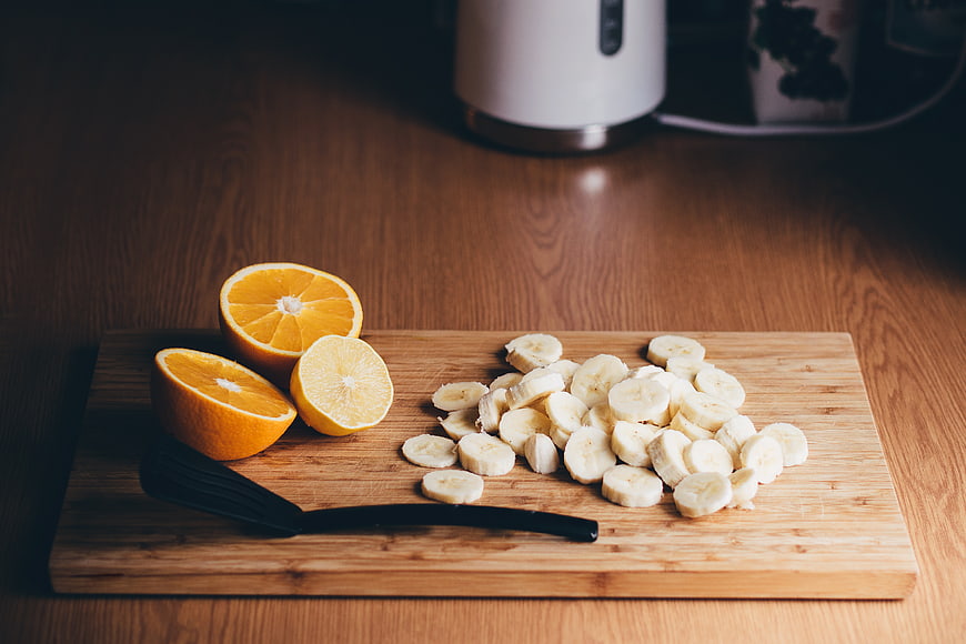 Sliced bananas and citrus fruits on a wooden cutting board
