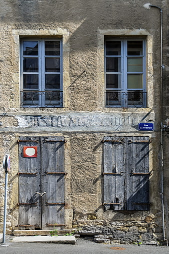 Old French building facade with weathered wooden shutters and door