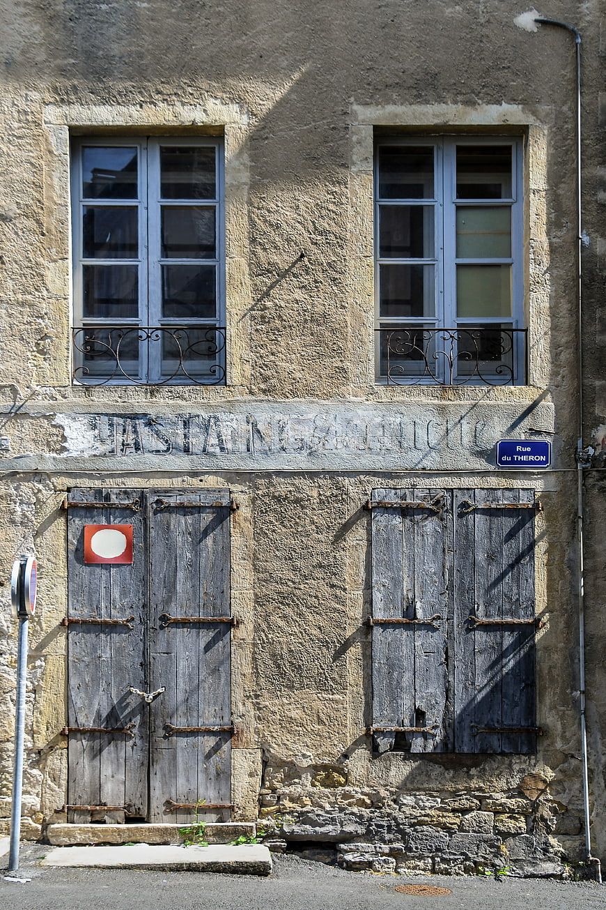 Old French building facade with weathered wooden shutters and door