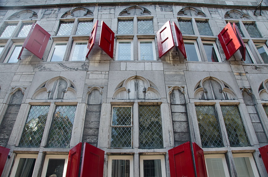 Red shutters on historic stone building facade in Utrecht