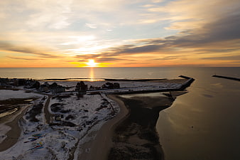 Aerial View of Snowy Coastal Village at Golden Sunset