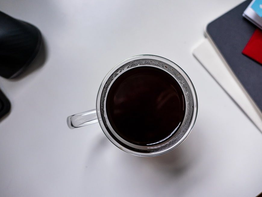 Top View of Black Coffee in Glass Mug on White Desk