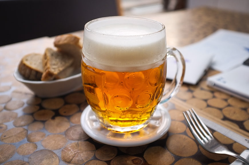 Glass of draft beer with bread on wooden table