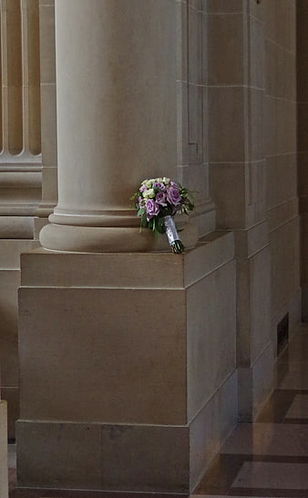 Purple and white wedding bouquet resting on stone pillar
