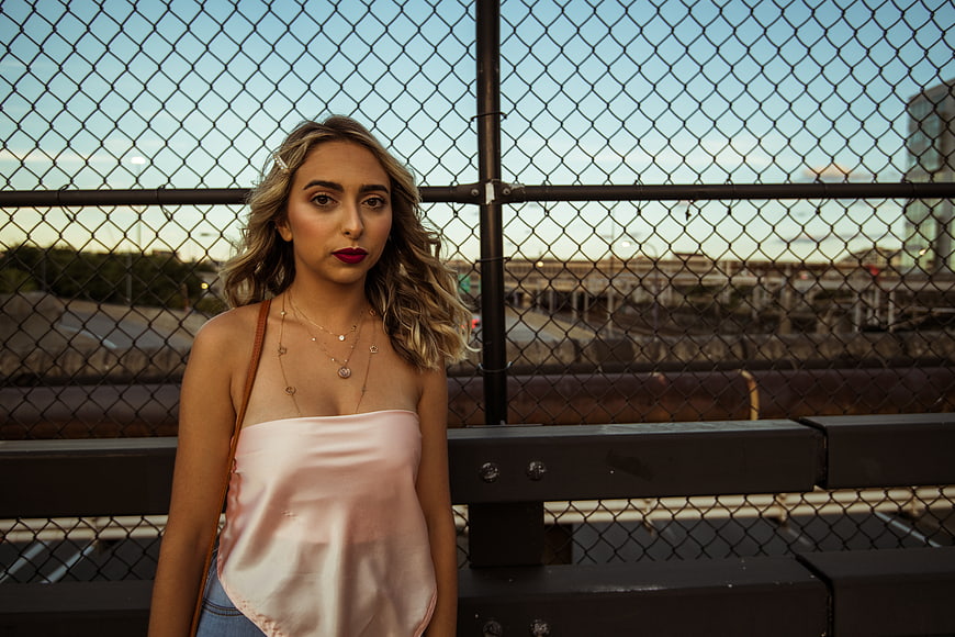 Stylish Woman in Pink Top Against Chain Link Fence