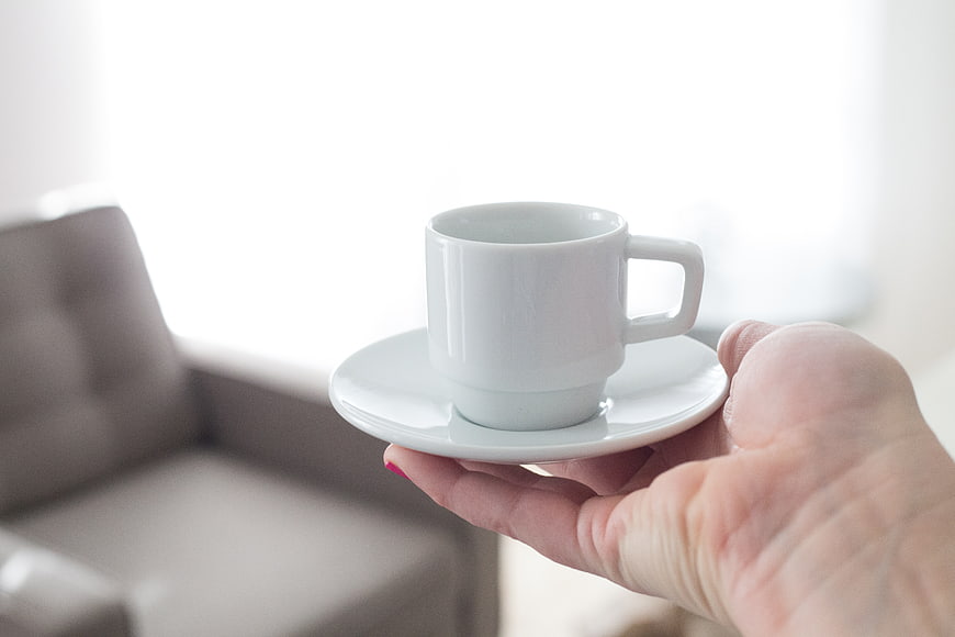 Hand Holding White Coffee Cup on Saucer