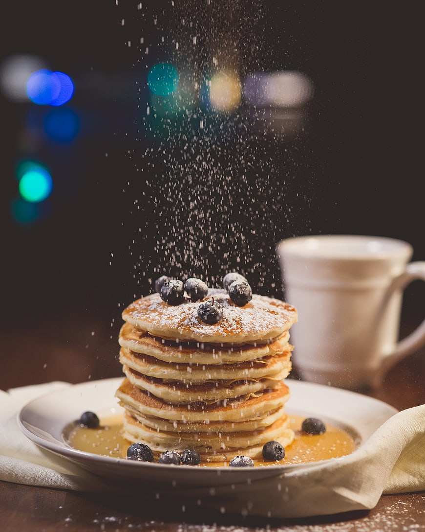 Stack of blueberry pancakes with powdered sugar and coffee