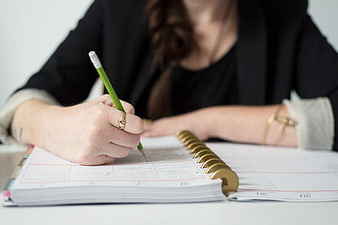 Woman Writing in Planner with Green Pencil