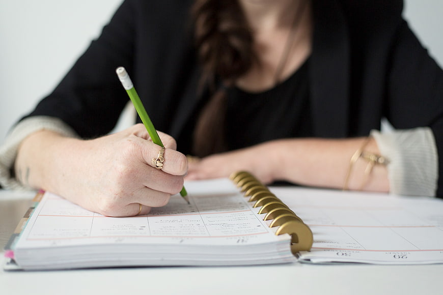 Woman Writing in Planner with Green Pencil